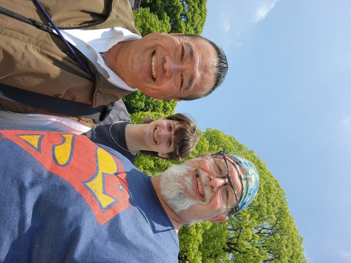 Selfie of three smiling travellers posing outdoors under a clear blue sky