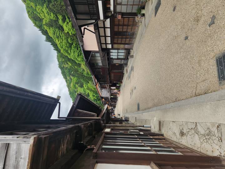 Empty stone-paved street lined with dark-timbered Edo-era houses on an overcast day