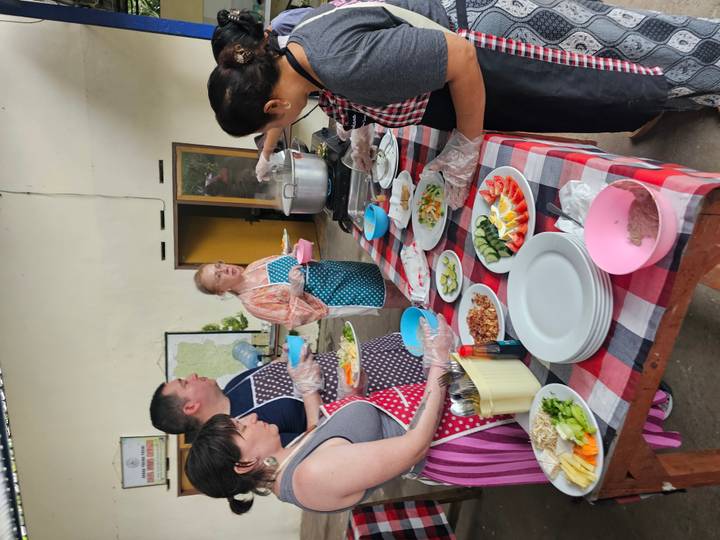 Cooking class participants preparing plates of sliced vegetables on checkered table.