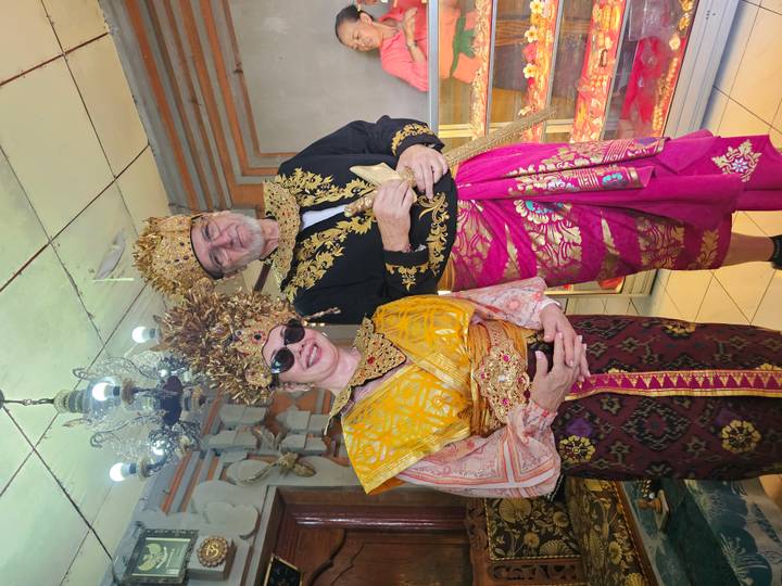 Visitors dressed in elaborate traditional Balinese royal costumes posing indoors.