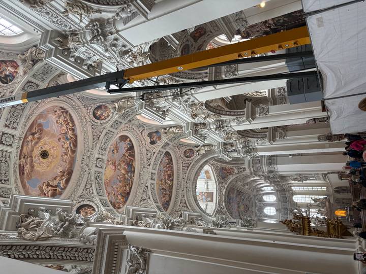 Ornate baroque cathedral interior with elaborate ceiling frescoes under restoration scaffolding