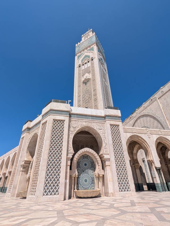 Close-up of the ornate Hassan II Mosque minaret rising sharply into a clear blue sky.
