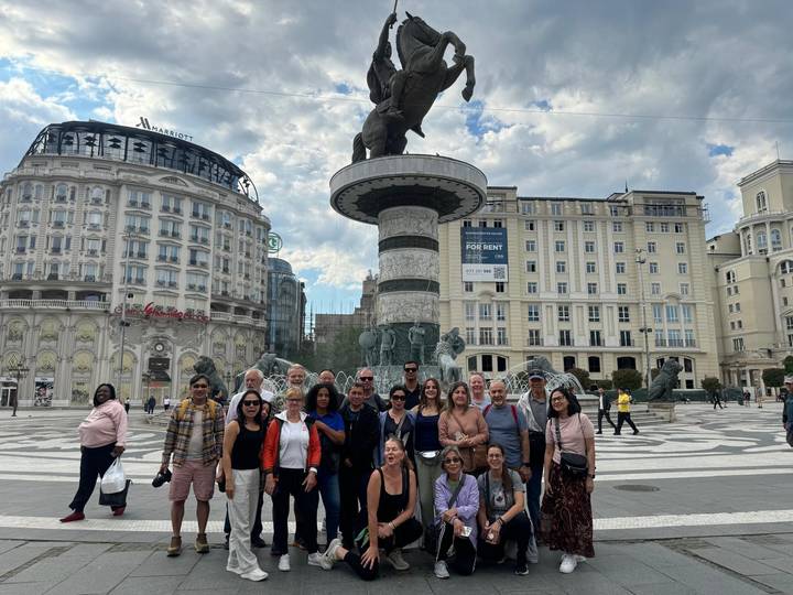 Tour group gathered in Macedonia Square before the Warrior on a Horse fountain with grand hotels behind.