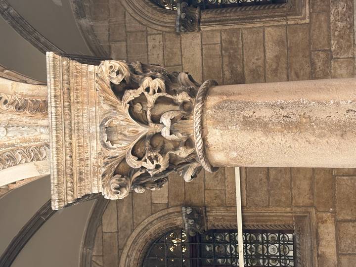 Close-up of an ornate carved Corinthian column capital in light stone.