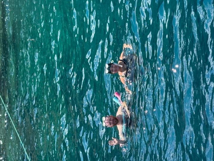 Two snorkellers smiling while floating in clear teal sea water.