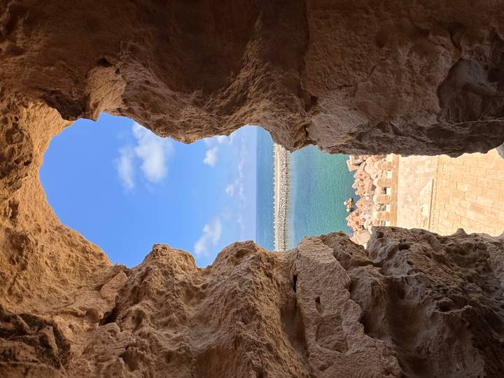 Framed sea view through a rocky window looking over a stone breakwater and turquoise water