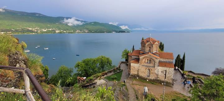 Church of St John at Kaneo perched above the tranquil blue waters of Lake Ohrid with mountains beyond