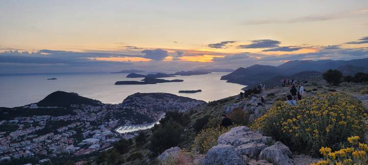 Sunset view over Dubrovnik, surrounding islands and the Adriatic from a rocky hillside sprinkled with yellow flowers
