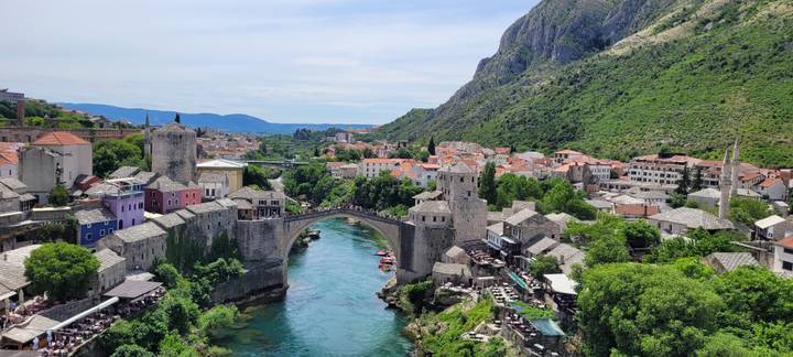 Classic postcard view of Mostar's Old Bridge arching over emerald Neretva River amid orange rooftops