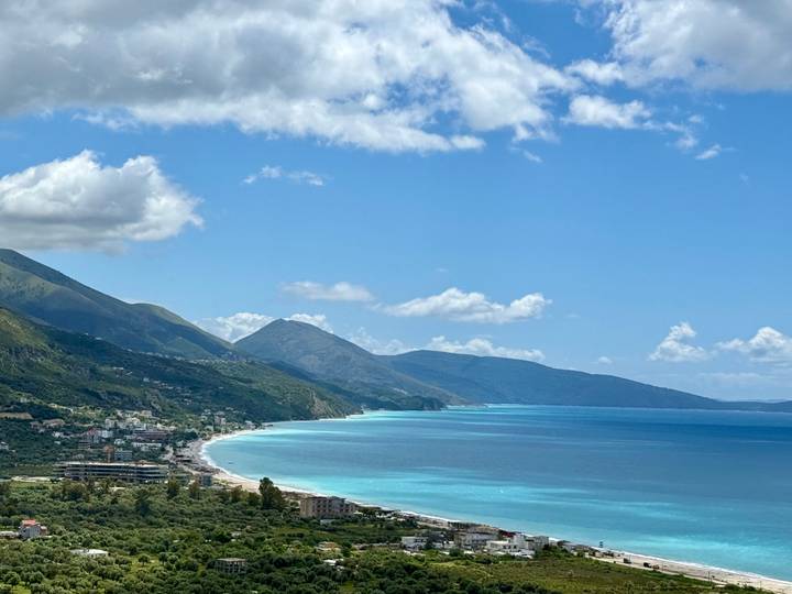 Turquoise Adriatic coastline with steep mountains and small seaside towns beneath a bright sky.