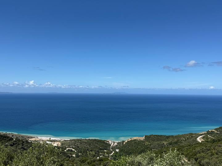 Minimalist view of deep blue open sea meeting a clear horizon beneath a cloud-dotted sky.