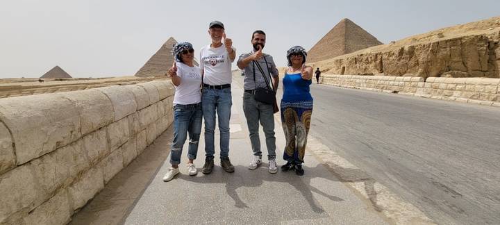 Travelers giving thumbs-up on road beside the Giza pyramids
