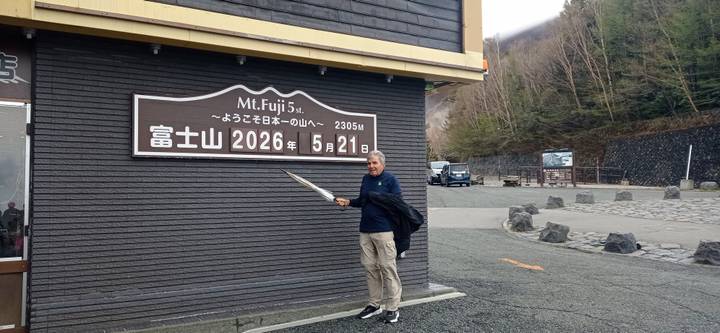 Traveller posing with umbrella beside the elevation sign at Mount Fuji’s 5th Station.