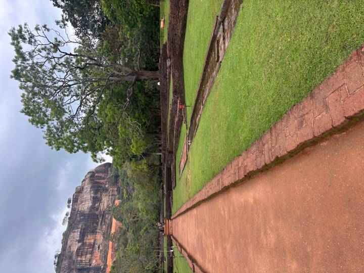 Pathway leading toward the massive Sigiriya rock fortress surrounded by manicured gardens.
