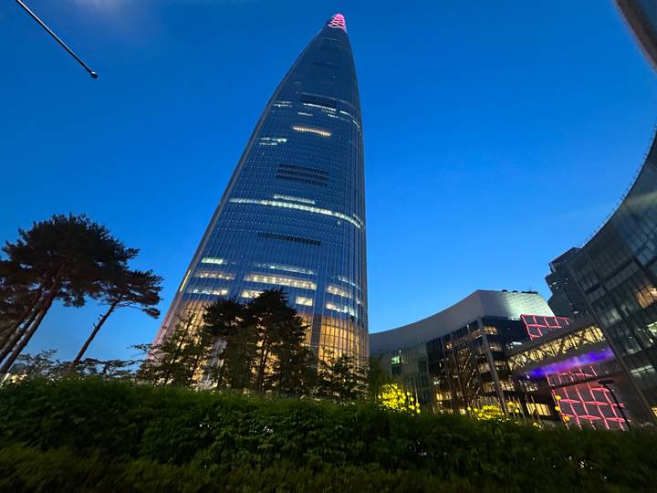 Night view looking up at Lotte World Tower illuminated against a deep blue sky