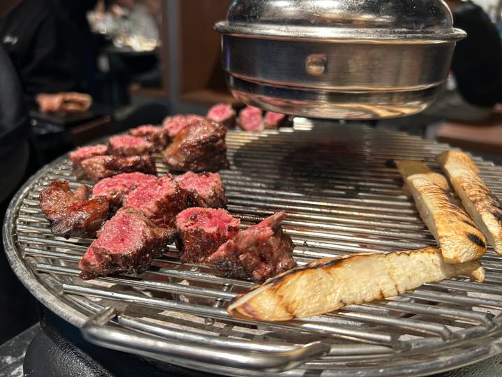Close-up of sizzling pieces of beef and mushrooms on a Korean BBQ grill
