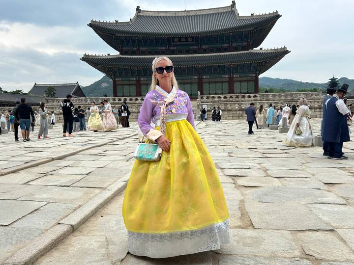 Woman dressed in bright hanbok posing in front of Gyeongbokgung Palace courtyard