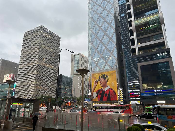 Urban streetscape of Gangnam with modern high-rise buildings and large billboard of a footballer