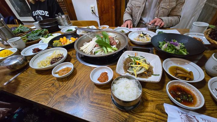 Traditional Korean table filled with sizzling hotpot, side dishes and rice ready to share between diners.