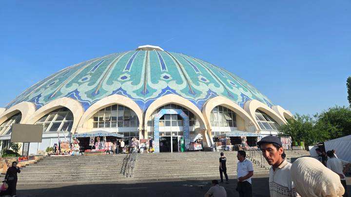 Domed Chorsu Bazaar in Tashkent displays intricate blue-green tile patterns above busy steps.