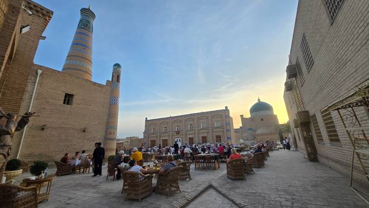 Courtyard café fills with diners at sunset beneath Khiva’s distinctive minarets.