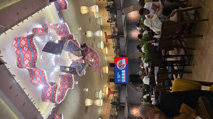 Stylish Uzbek restaurant interior with vivid patterned ceiling décor and diners below.