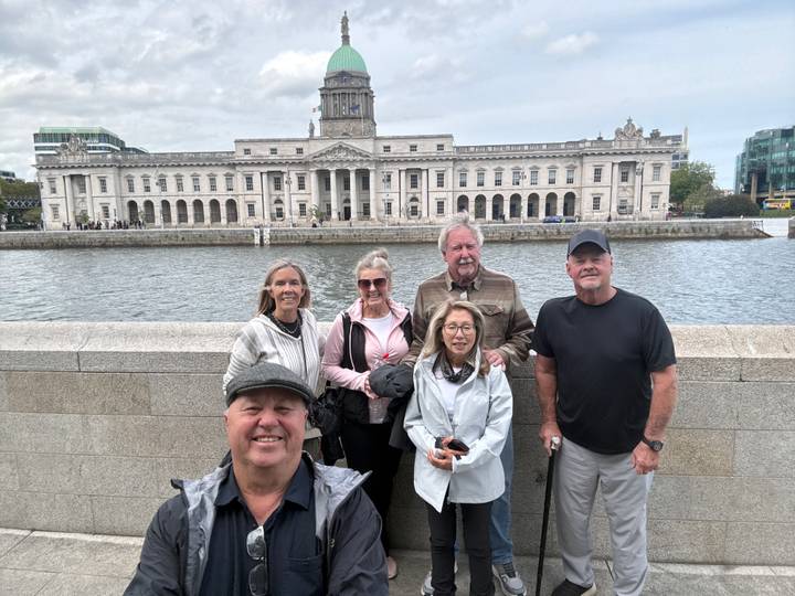 Tour group standing on a bridge with Dublin's Custom House and River Liffey in the background.