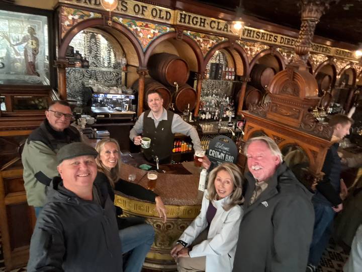 Group gathered around a Victorian wooden bar inside the ornate Crown Liquor Saloon.