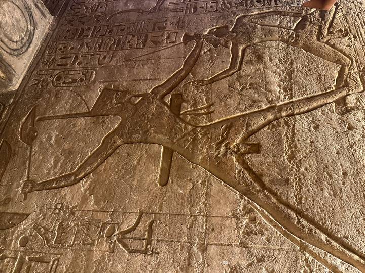 Close-up of deep-relief carving of an ancient Egyptian warrior figure on sandstone.