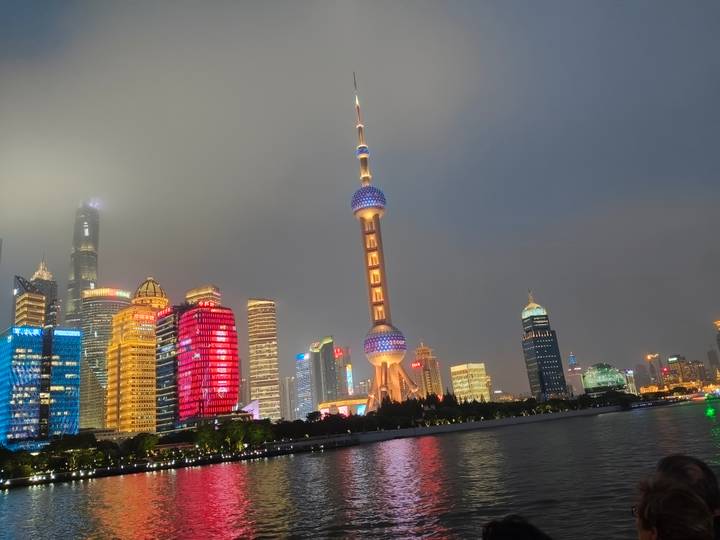 Night skyline of Shanghai with brightly lit Oriental Pearl Tower reflected on the river
