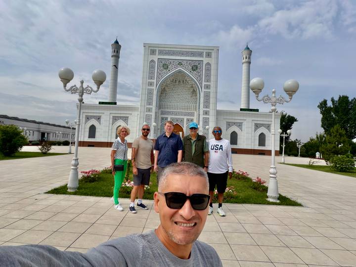 Travellers taking a selfie in front of the ornate white Minor Mosque with blue domes and minarets.