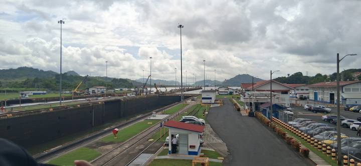 Wide view of Miraflores Locks on the Panama Canal with ships transiting and lush hills beyond.