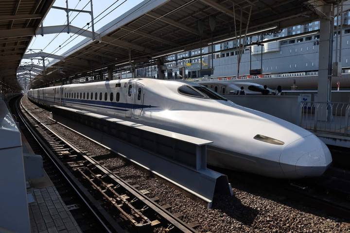 Sleek white Shinkansen bullet train waiting at a covered station platform