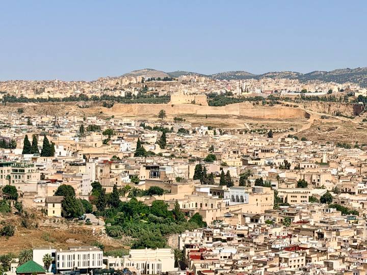 Expansive panoramic view over the densely packed beige buildings and ancient walls of Fes