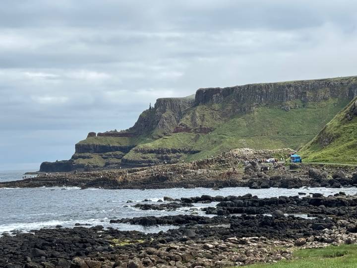 Wide coastal scene of Giant's Causeway with visitors walking among basalt rocks