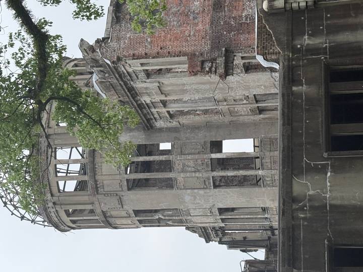 Close view of the concrete and brick ruins of Hiroshima’s Atomic Bomb Dome with tree branch above.