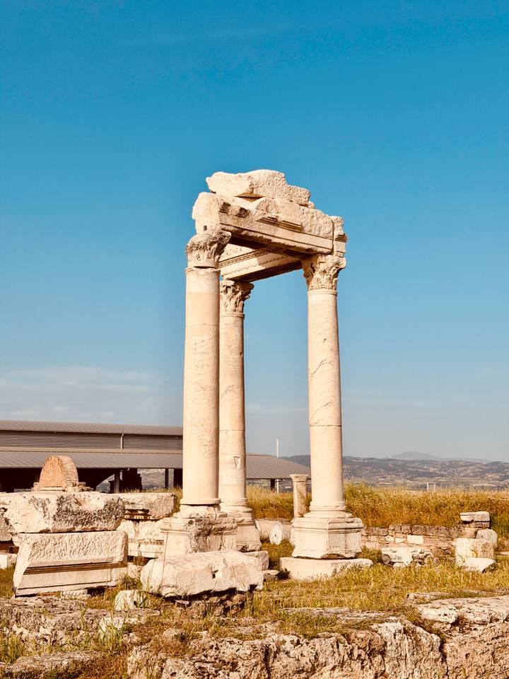Standing marble columns of an ancient Roman gateway set against a clear blue Anatolian sky.