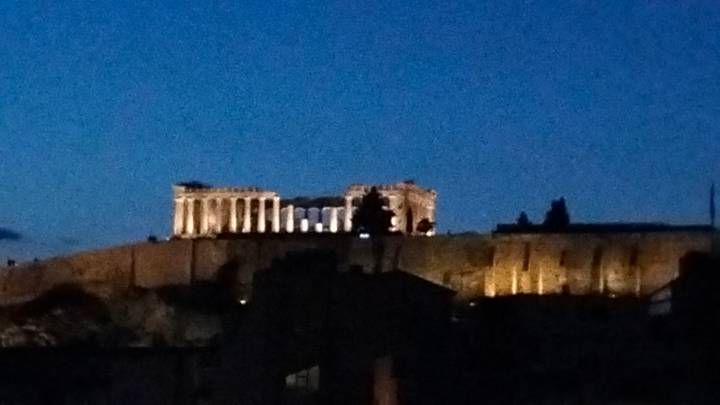 Night view of illuminated Acropolis hill against deep blue sky.