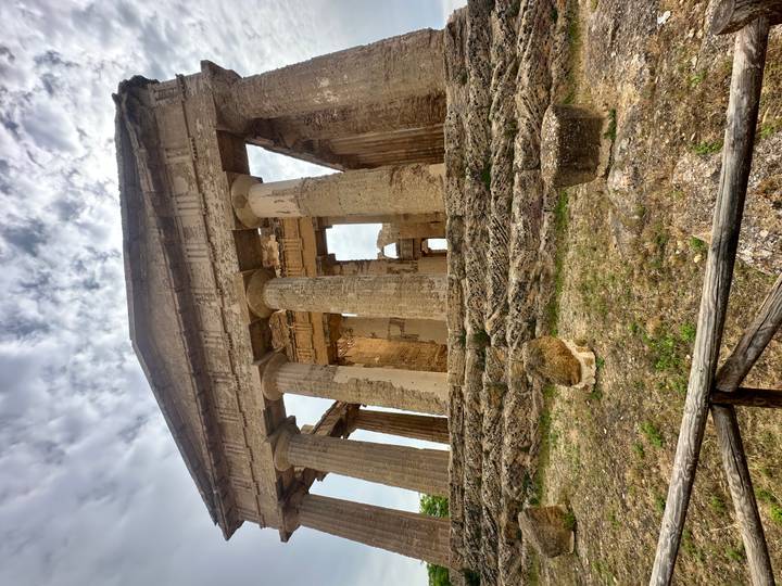 Ancient Greek temple ruins with massive Doric columns under a partly cloudy sky.