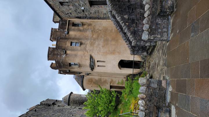 A small round tower and stone stairways inside a Scottish castle complex on a wet day.