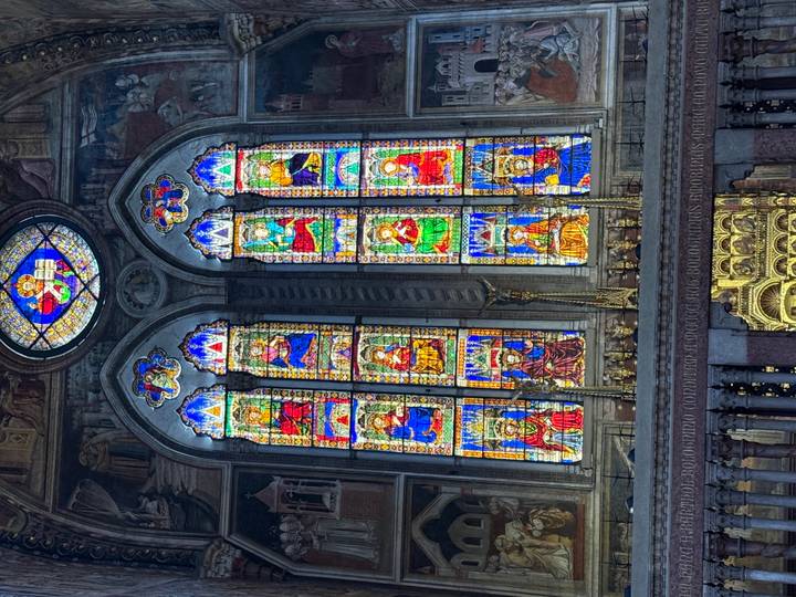 Vibrant stained-glass windows inside an ornate Italian cathedral.