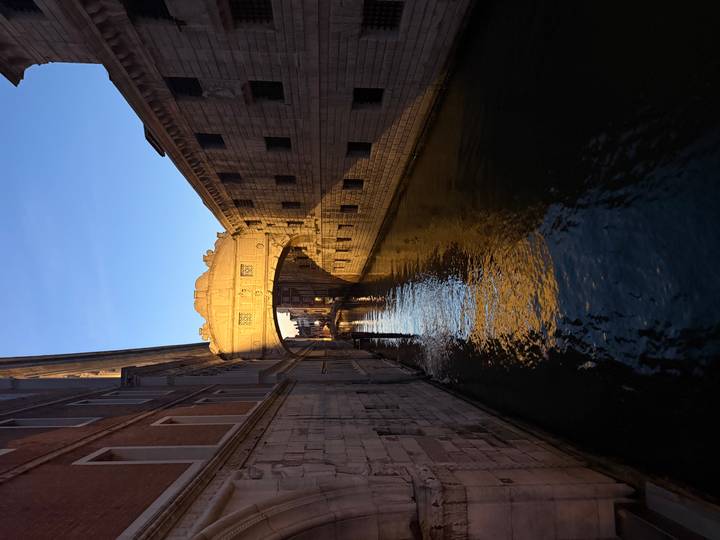 Golden light illuminates Venice's Bridge of Sighs over a quiet canal.
