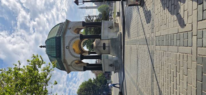Historic German Fountain stands in an empty plaza under patterned morning clouds.