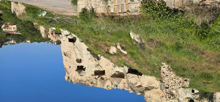 Sun-lit cave dwellings carved into a rocky hillside in Cappadocia.