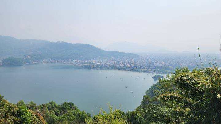 Hazy panoramic view over a large lake and sprawling city surrounded by green hills