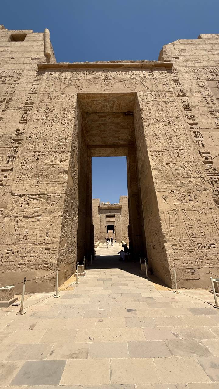 Towering hieroglyph-covered temple gateway framing a deep blue sky.