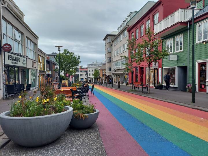 Colorful rainbow-painted pedestrian street lined with shops and cafés in Reykjavik.