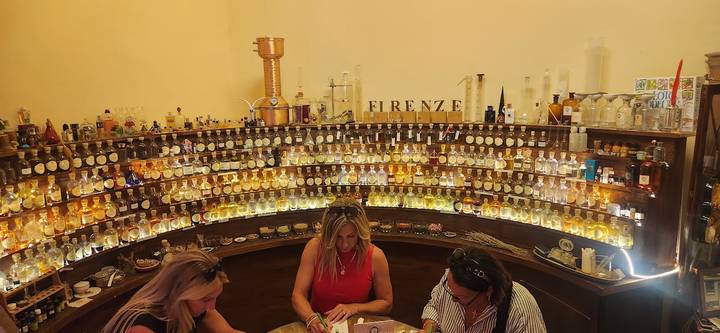 Interior workshop with shelves of illuminated perfume bottles where participants craft fragrances