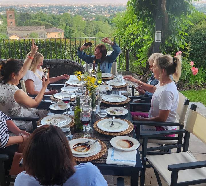 Friends sharing an alfresco dinner around a set table with wine and laughter in a garden