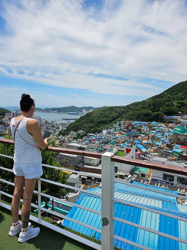 A traveler views the colorful hillside homes of Gamcheon Culture Village overlooking Busan’s harbor.